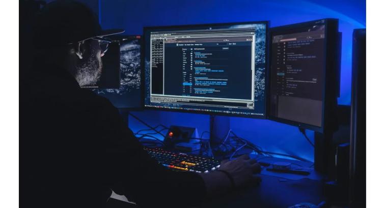 Man working on computer in dark room with blue lights