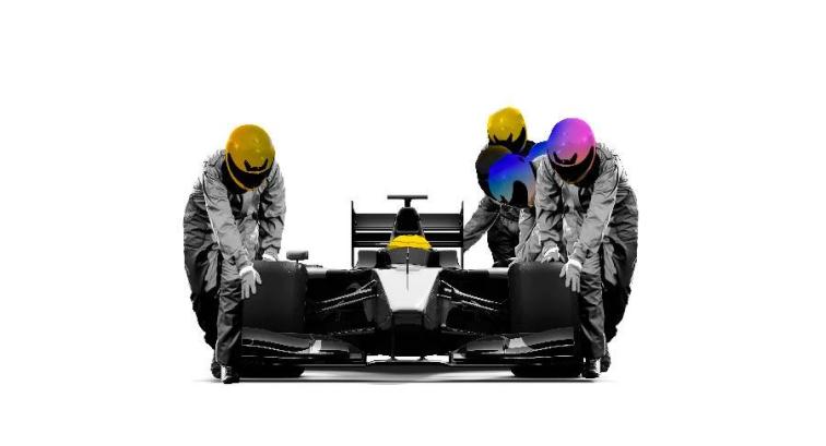 Race car with a driver in a helmet in it, with three other people in helmets pushing the race car along.