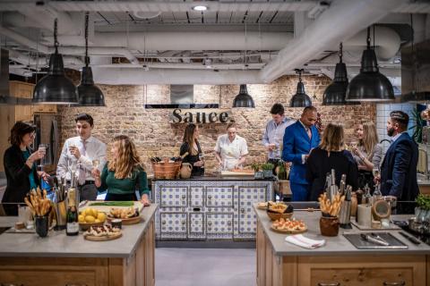 People gathered around a chef in a cooking class at Sauce by the Langham